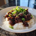 A close-up of Instant Pot Korean Beef and Rice Bowls topped with green onions and sesame seeds.