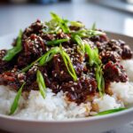 Close-up of Instant Pot Korean Beef and Rice Bowls, featuring saucy beef over white rice, topped with green onions and sesame seeds.