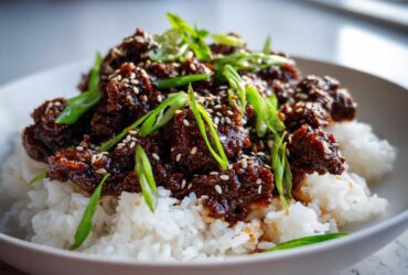 Close-up of Instant Pot Korean Beef and Rice Bowls, featuring saucy beef over white rice, topped with green onions and sesame seeds.