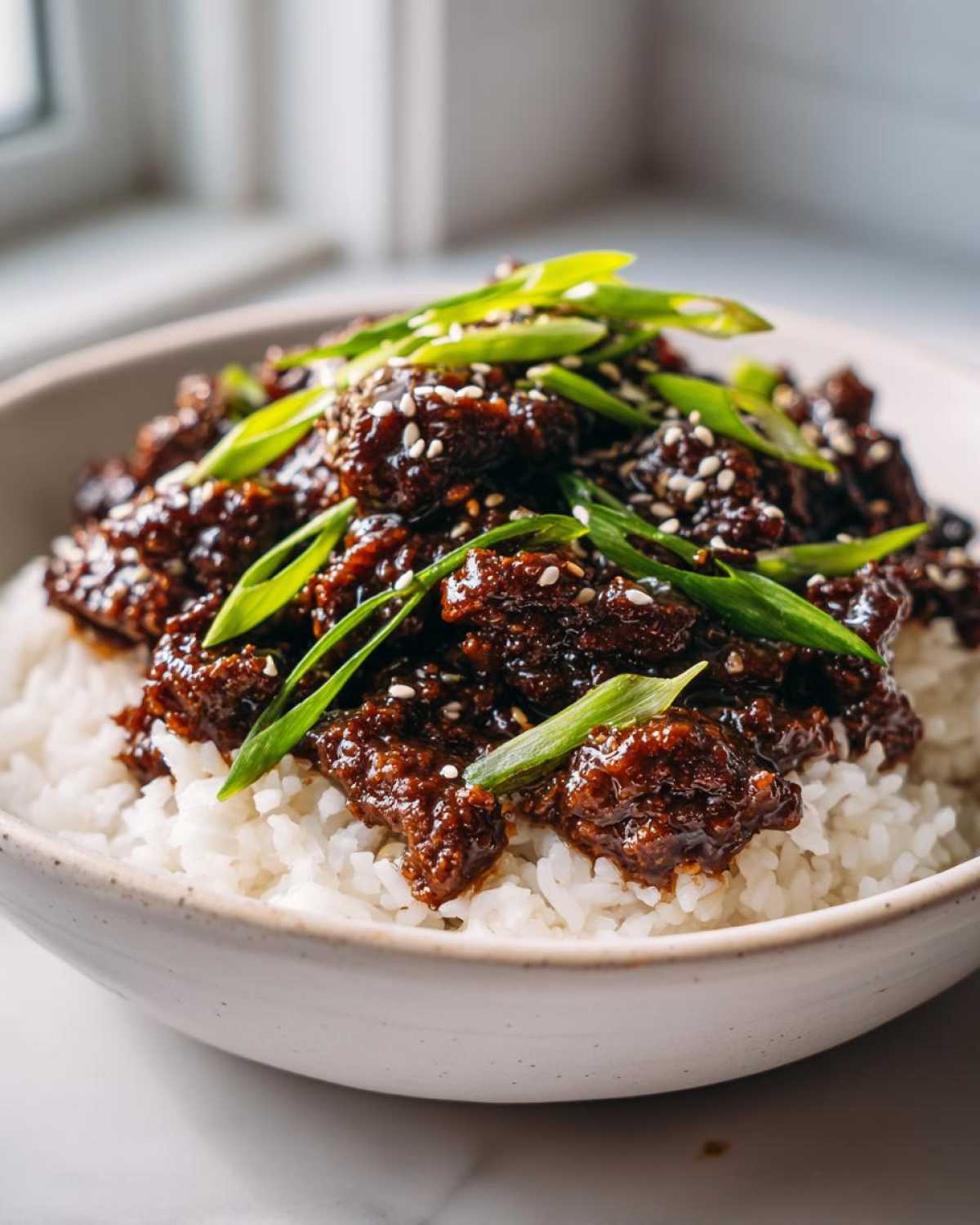 Close-up of Instant Pot Korean Beef and Rice Bowls topped with sesame seeds and green onions.
