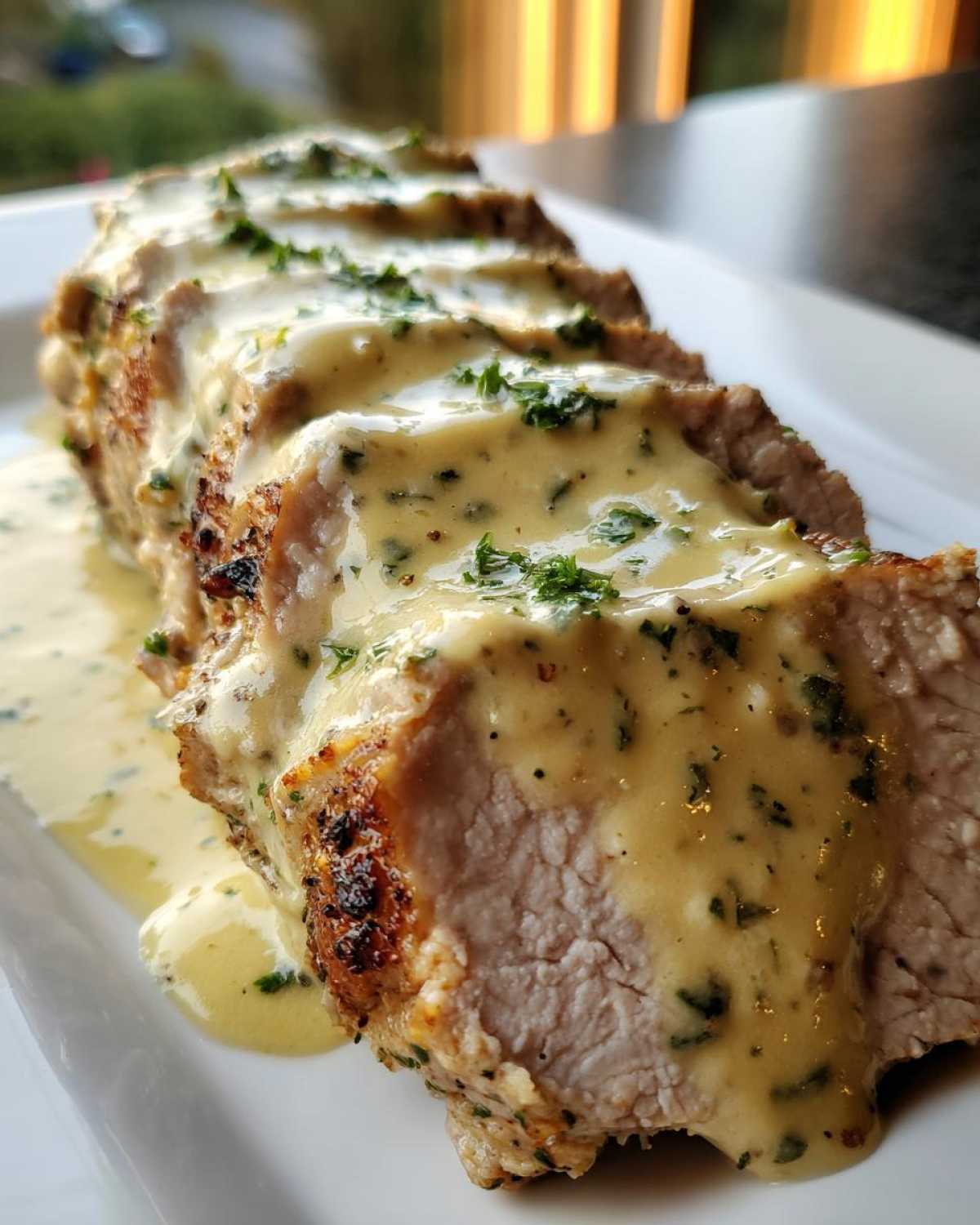 Close-up of sliced Keto Creamy Garlic Herb Pork Tenderloin covered in a rich, creamy garlic herb sauce and garnished with parsley.