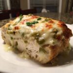 Cross-section of Keto Creamy Jalapeno Popper Chicken topped with melted cheese and green peppers.