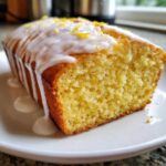 Close-up of a moist Lemon Loaf drizzled with white icing and topped with lemon zest.