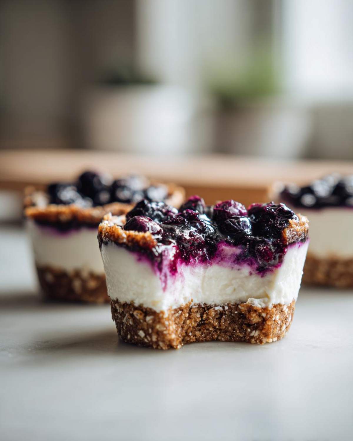 A close-up of a No-Bake Blueberry Cheesecake Oat Cup with a bite taken out, showing the creamy filling and oat crust.