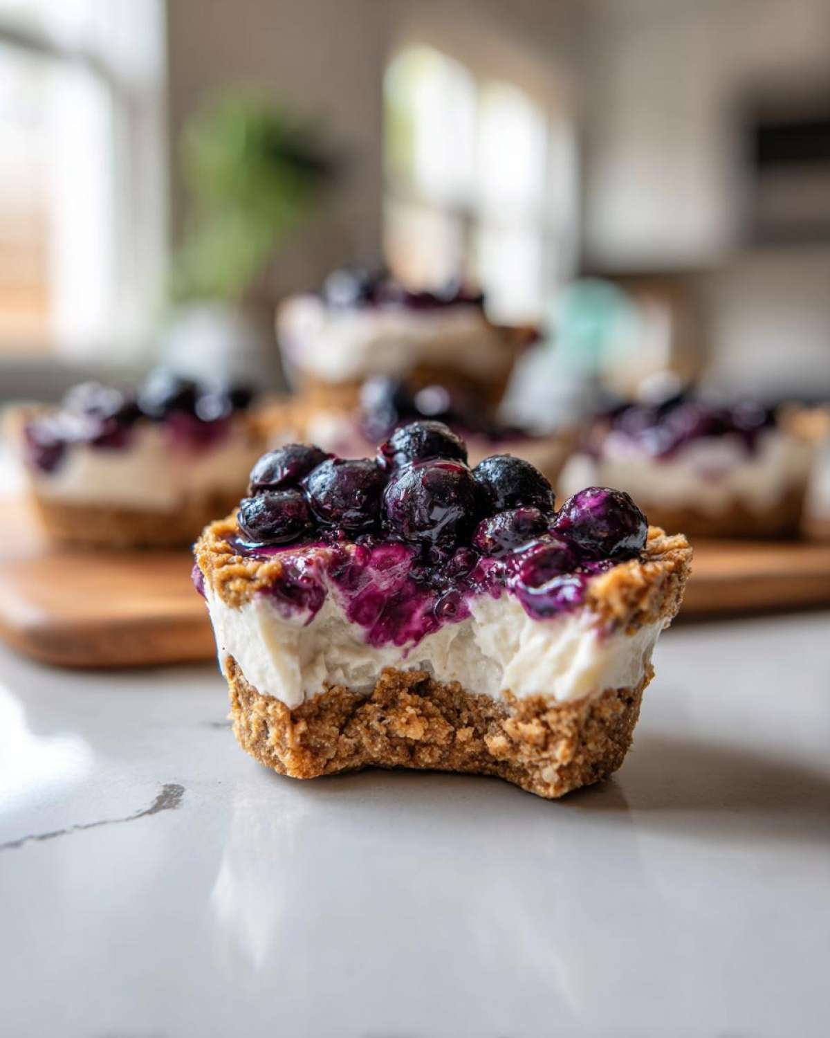 Close-up of a No-Bake Blueberry Cheesecake Oat Cup with a bite taken out, showing creamy filling and blueberry topping.
