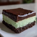 A square slice of No-Bake Chocolate Mint Icebox Bars showing chocolate crust, mint layer, and ganache topping.