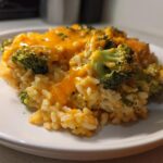 Close-up of a serving of One-Pot Creamy Broccoli Cheddar Rice topped with melted cheddar cheese and visible broccoli florets.