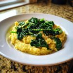 A close-up of a serving of One-Pot Creamy Spinach Parmesan Polenta topped with wilted spinach and grated cheese.
