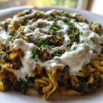 A close-up of a serving of Persian noodle soup (Ash Reshteh style) topped generously with white yogurt sauce and fresh chopped herbs.