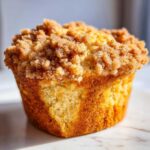 A close-up, appetizing photo of a single Pineapple Muffins With Crumb Topping featuring a thick, sugary cinnamon crumb topping.
