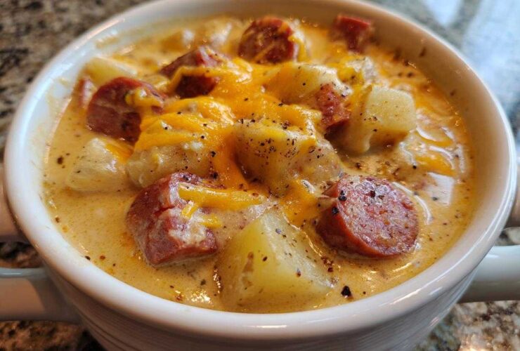 Close-up of a creamy Pioneer Woman Sausage Potato Chowder topped with melted cheddar cheese and black pepper.