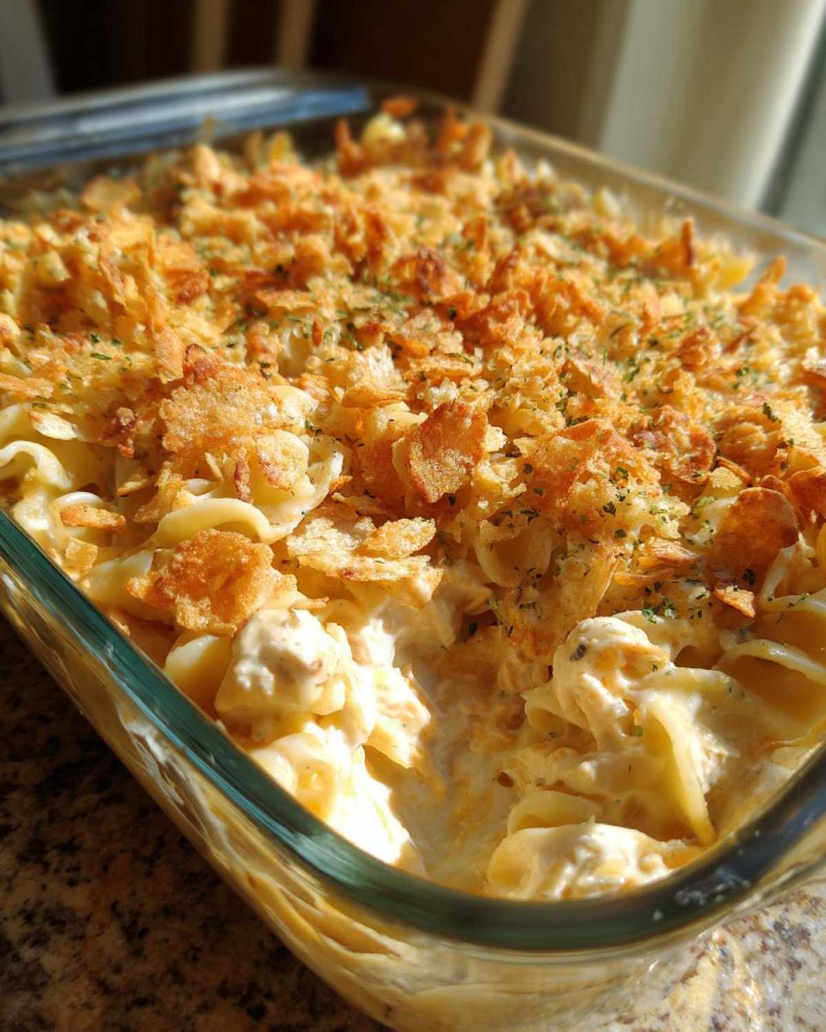 Close-up of creamy Pioneer Woman Tuna Noodle Casserole in a glass dish, topped with golden crushed chips.