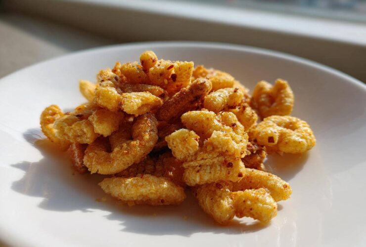 Close-up of a small pile of Savory Garlic Butter Chex Mix Crunchy Snack coated in seasoning on a white plate.