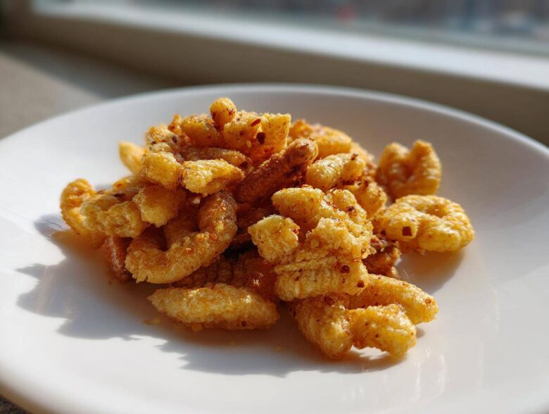 Close-up of a small pile of Savory Garlic Butter Chex Mix Crunchy Snack coated in seasoning on a white plate.