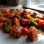 Close-up of crispy, glazed Sheet Pan Crispy Honey Mustard Tofu mixed with roasted broccoli and red peppers.