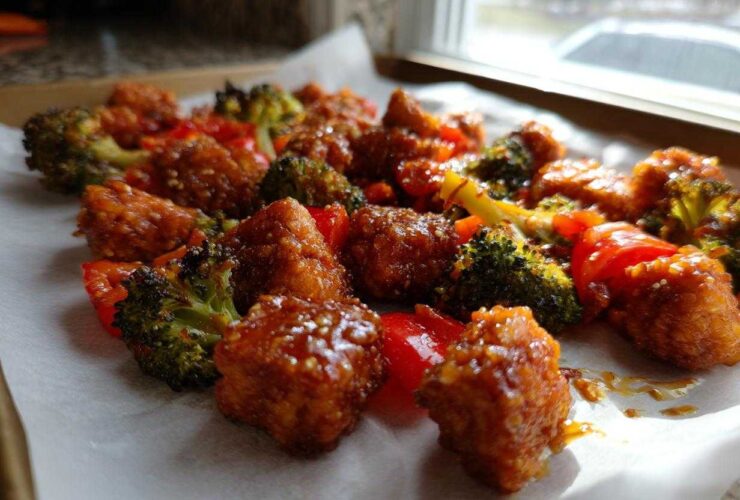 Close-up of crispy, glazed Sheet Pan Crispy Honey Mustard Tofu mixed with roasted broccoli and red peppers.