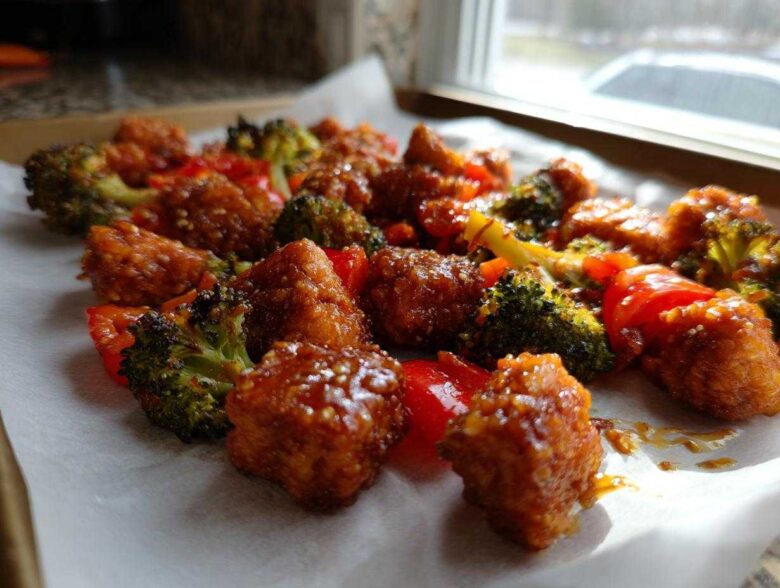 Close-up of crispy, glazed Sheet Pan Crispy Honey Mustard Tofu mixed with roasted broccoli and red peppers.