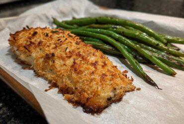 Close-up of Sheet Pan Crispy Parmesan Tilapia with Green Beans served on parchment paper.