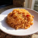 A mound of Simple & Fluffy Mexican Rice, perfectly cooked and orange-red, served on a white plate.