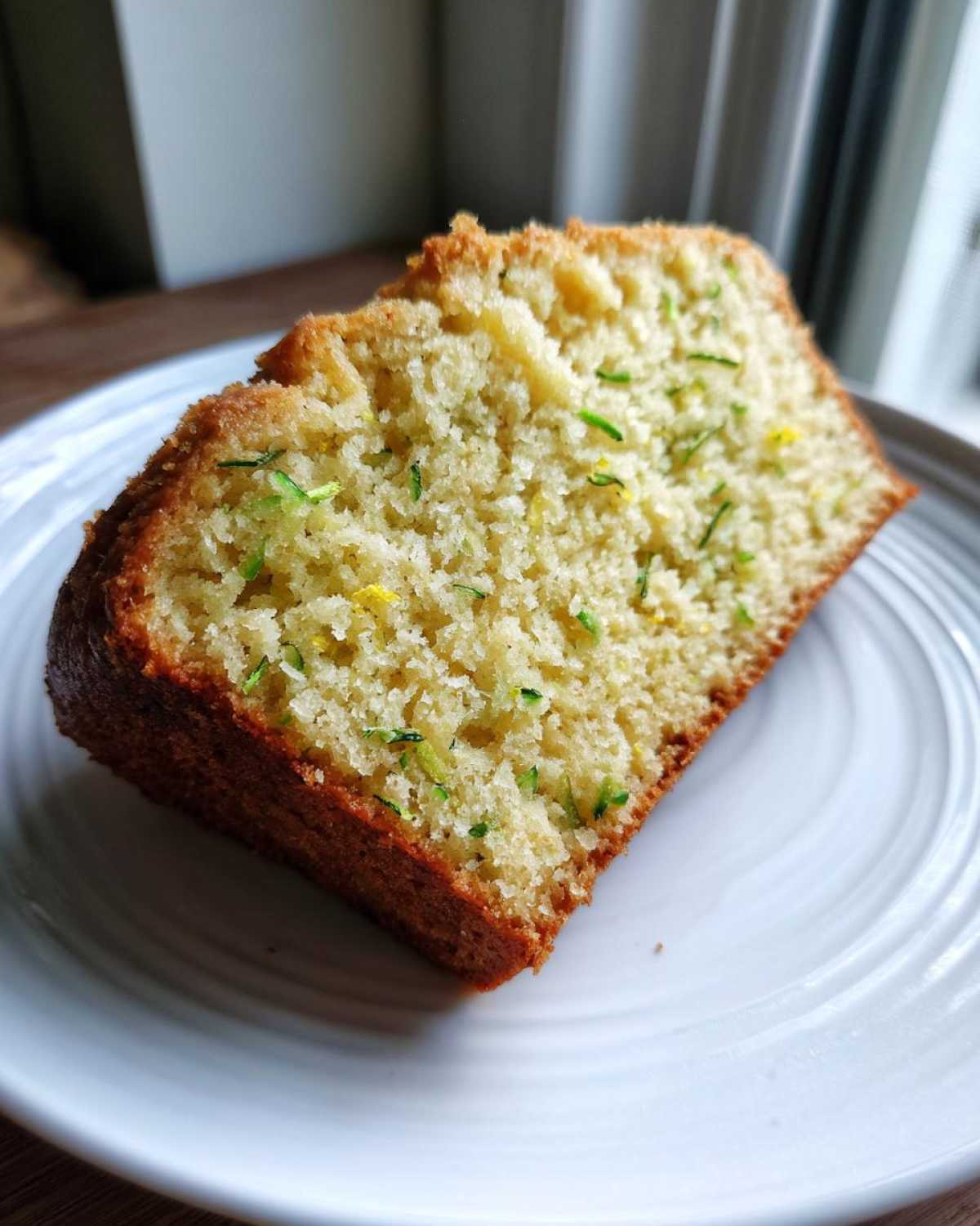 Close-up of a moist slice of Gluten-Free Lemon Zucchini Bread showing green zucchini shreds.