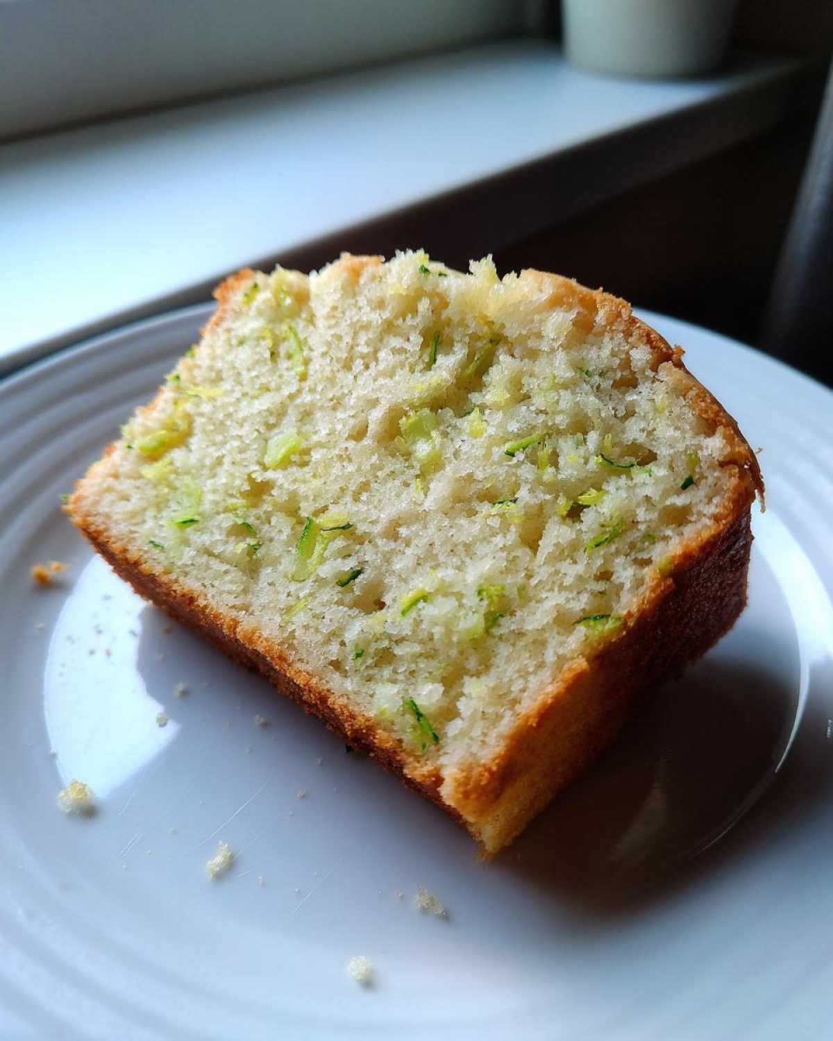 Close-up of a moist slice of Gluten-Free Lemon Zucchini Bread showing shredded green zucchini baked into the light crumb.