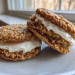 Two soft oatmeal cream pies stacked with creamy white filling, displayed on a white plate.