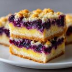 Two stacked squares of Gluten-Free Lemon Blueberry Layer Bars showing the crust, lemon layer, and blueberry topping.