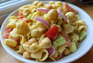 Close-up of Vegan Creamy Lemon Chickpea Pasta Salad with pasta shells, chickpeas, tomatoes, red onion, and celery.