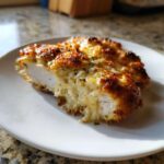Cross-section of juicy Baked Caesar Chicken with Creamy Parmesan Sauce, showing a golden-brown, cheesy top.