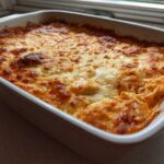 A close-up of hot, bubbly Buffalo Chicken Dip with a perfectly browned and melted cheese topping in a white baking dish.