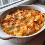 Close-up of hot, bubbly Buffalo Chicken Dip topped with melted, browned cheese.