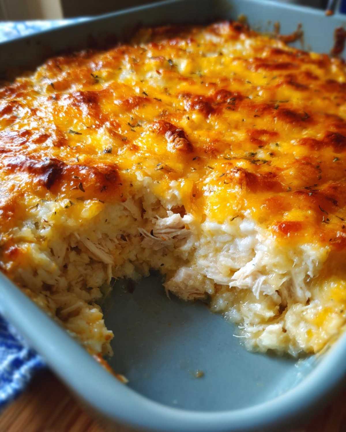 Close-up of a baked Chicken Cauliflower Rice Casserole with a golden, melted cheese topping and visible shredded chicken inside.