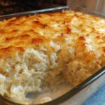 Close-up of a baked Chicken Cauliflower Rice Casserole with a golden, melted cheese topping in a glass dish.