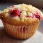A single, golden-brown Cottage Cheese Strawberry Muffins, featuring visible bright red strawberries baked into the top.