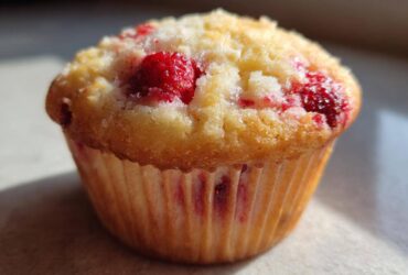 A single, golden-brown Cottage Cheese Strawberry Muffins, featuring visible bright red strawberries baked into the top.