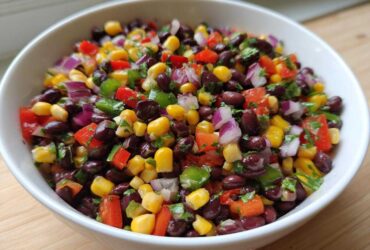 Close-up of vibrant Cowboy Caviar Dip featuring black beans, corn, red onion, and peppers in a white bowl.