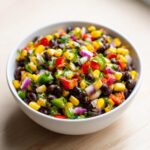Close-up of colorful Cowboy Caviar Dip featuring black beans, corn, red peppers, and red onion.
