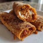Close-up of Crispy Oven Rolled Chicken Taquitos Delight, showing shredded chicken and sauce filling inside the golden, crispy shell.
