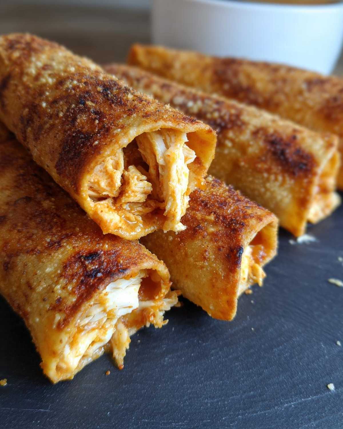 Close-up of crispy oven rolled chicken taquitos delight, showing shredded chicken filling inside the golden-brown tortilla.