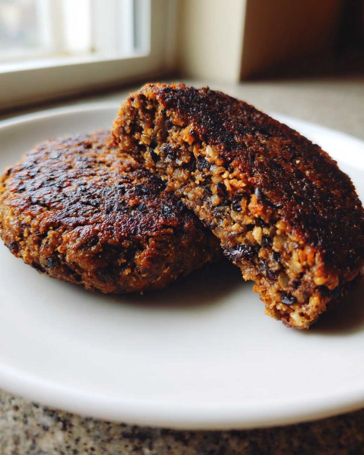 Close-up of a perfectly firm Black Bean Burger cut in half showing the hearty, textured interior.