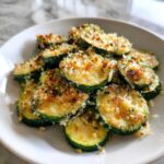 A white bowl filled with perfectly roasted, sliced zucchini topped with golden brown Garlic Parmesan Zucchini Roast topping.