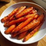 A close-up of perfectly roasted Glazed Honey Garlic Butter Roasted Carrots piled high in a white serving bowl.