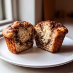 A Greek Yogurt Cinnamon Muffin cut in half showing the moist interior and cinnamon swirl topping.