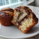 Close-up of Greek Yogurt Cinnamon Muffins, one cut open showing the moist interior and cinnamon swirl.