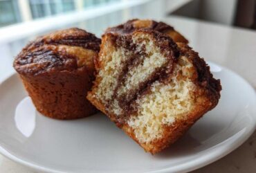 Close-up of Greek Yogurt Cinnamon Muffins, one cut open showing the moist interior and cinnamon swirl.