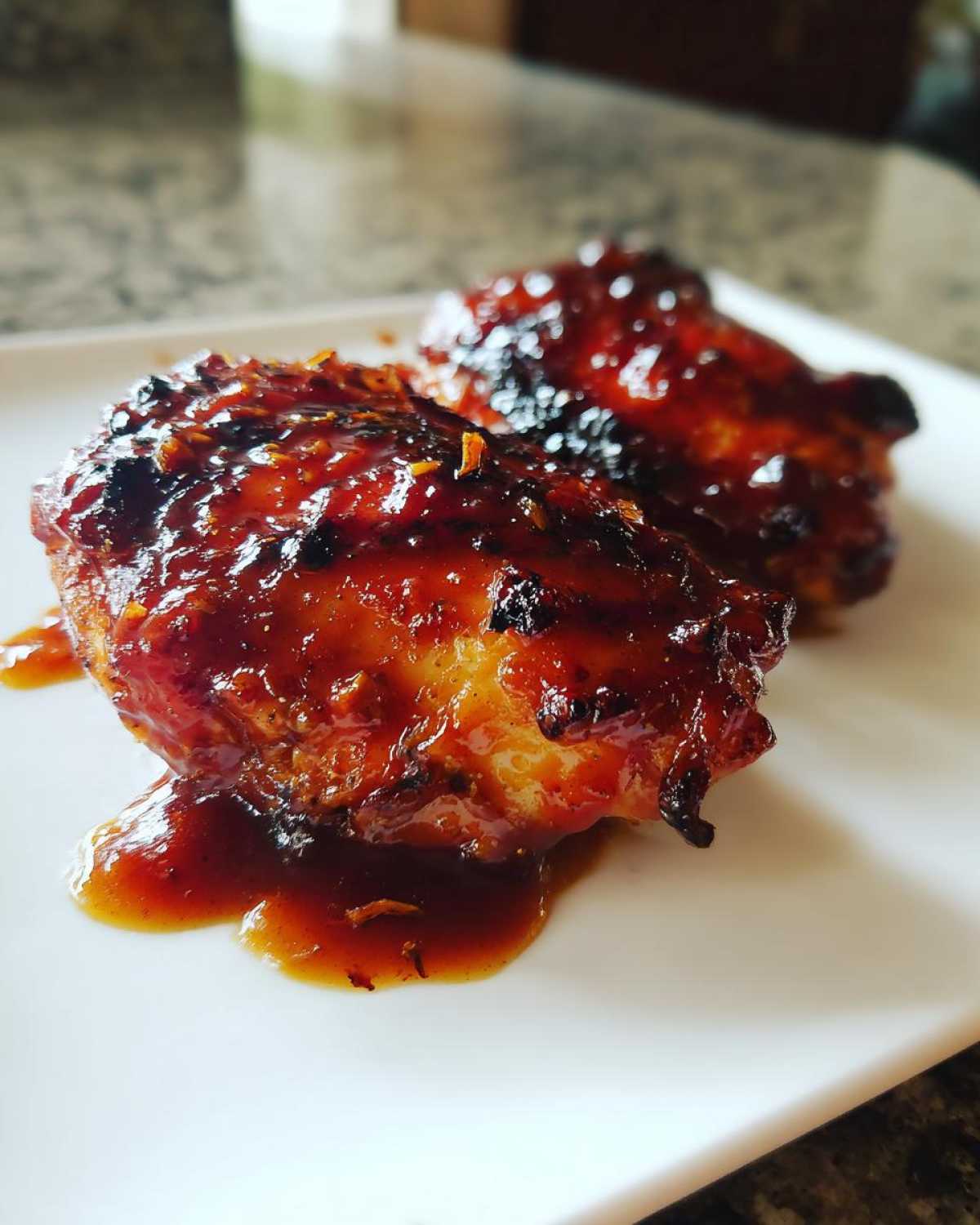 Close-up of two pieces of Hawaiian Huli Huli Chicken covered in a thick, glossy, caramelized glaze.