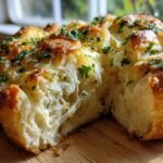 Close-up of cheesy Hawaiian Roll Garlic Bread showing a gooey cheese pull and fresh parsley topping.