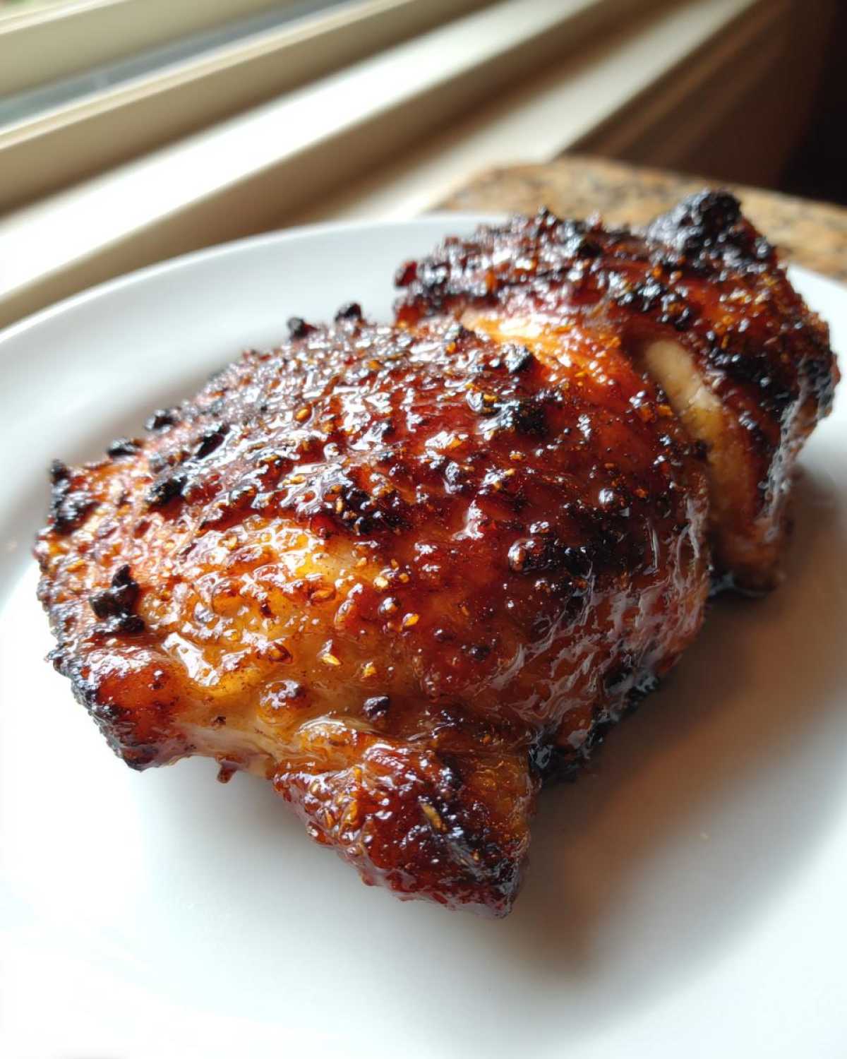 Close-up of two perfectly cooked Honey Garlic Boneless Chicken Thighs with a sticky, caramelized glaze.