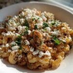 Close-up of Mexican Style Elote Pasta Salad topped with crumbled white cheese and cilantro.
