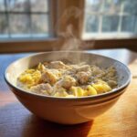 A steaming bowl of creamy Crack Chicken Noodle Soup with chunks of chicken and egg noodles, seasoned with pepper.